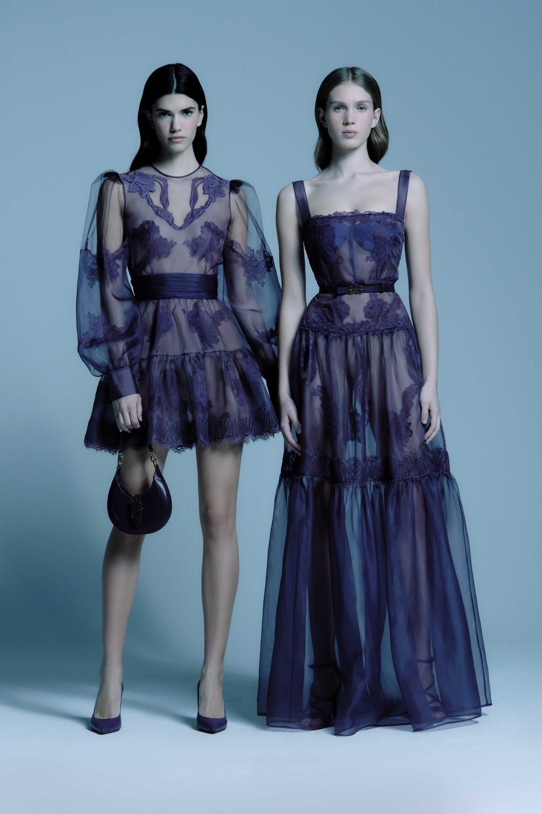 Due modelle Zuhair Murad in abiti da cerimonia viola con borsa a mezzaluna